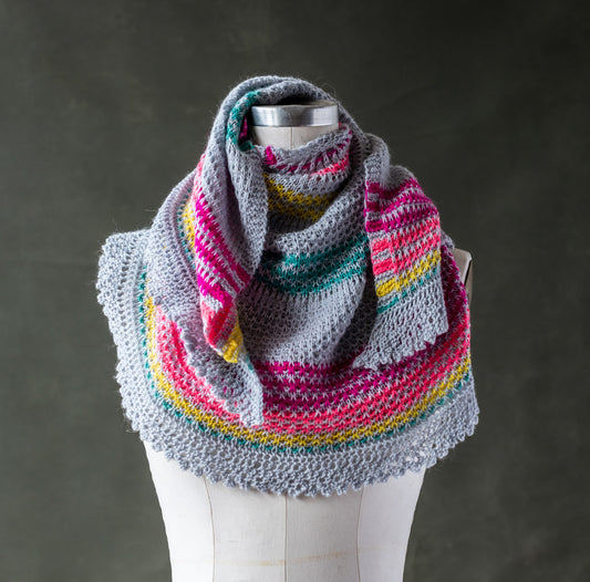 Half Circle Shawl in gray Perennial yarn with neon pink, coral, yellow, and green stripes on a cloth mannequin with a dark grey background