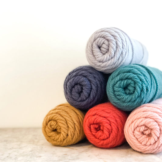 kelbourne woolens germantown bulky wool yarn skeins piled in a pyramid on a marble table against a white background